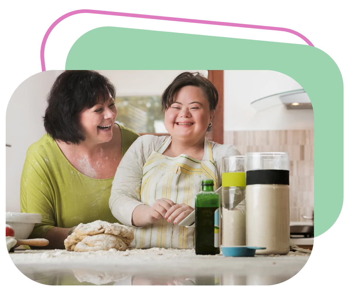 a young woman with down syndrome is smiling while preparing cookie dough in the kitchen with her caregiver